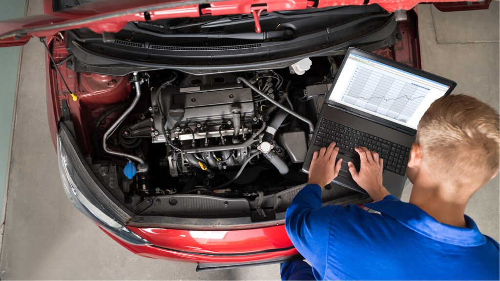 Mechanic under hood with laptop