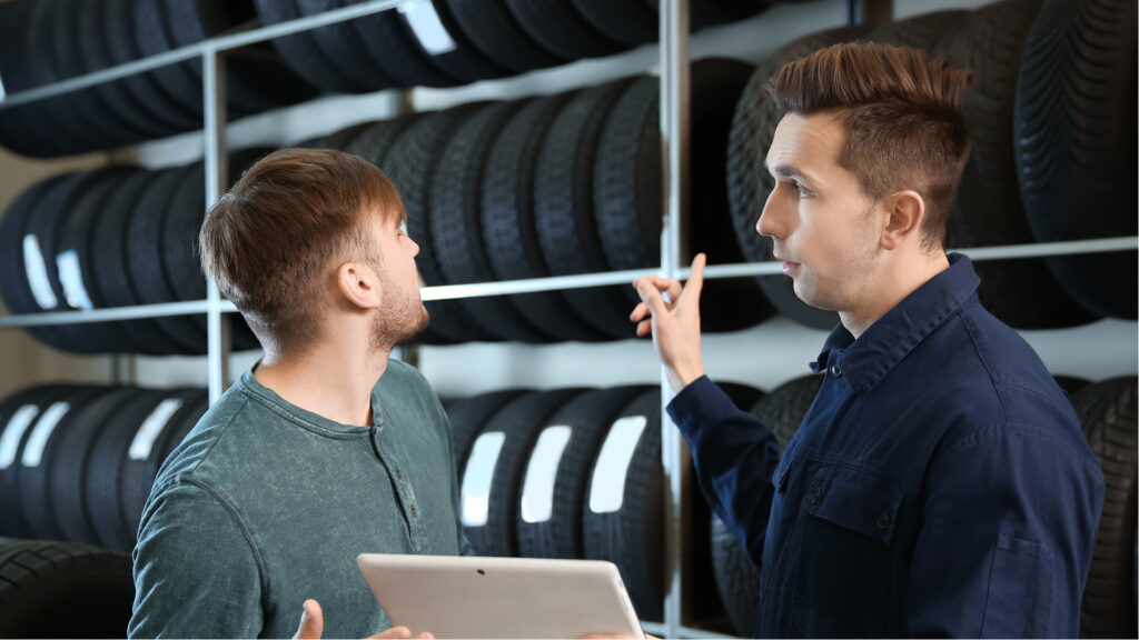Two men talking by tires