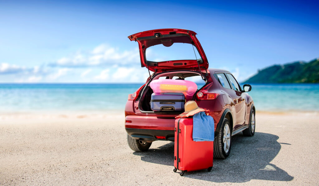Car and luggage on a beach represent summer marketing campaigns.